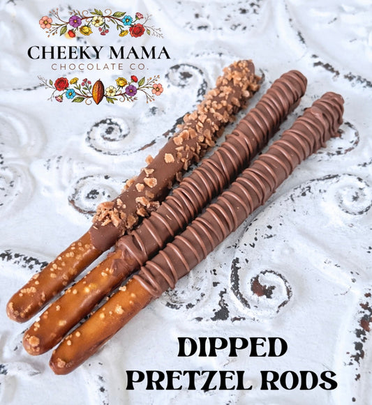 three chocolate-dipped pretzel rods on a decorative surface with 'Cheeky Mama Chocolate Co.' branding.